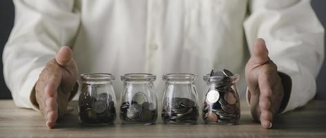 monedas en frasco de vidrio y en mesa de madera, ideas de ahorro futuro, jubilación foto