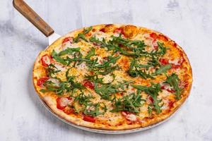 An angle shot of a spatula taking one piece of an arugula pizza. photo