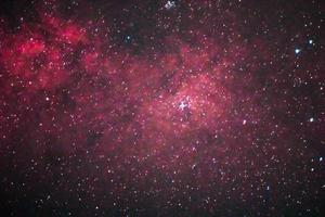 una galaxia colorida con estrellas predominantemente rojas y polvorientas en el espacio exterior foto