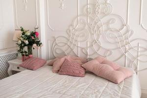 hermoso interior de dormitorio luminoso. dormitorio con cama grande. cama con almohadas rosas foto