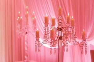 sobre la mesa hay un candelabro de cristal con velas. decoración para vacaciones o celebraciones con luz rosa. enfoque selectivo foto