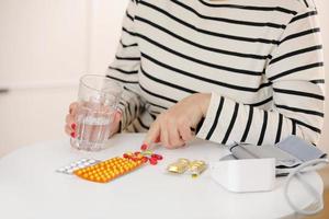 older woman hold glass of water and antibiotic aspirin pill feel unhealthy at home, sick mature female take daily dose of supplemolder woman hold glass of water. elderly healthcare concept. photo