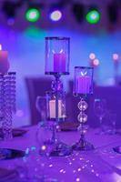 On the table is a candlestick made of crystal with white candles. Decoration for holiday or celebration with blue light. selective focus. wedding day. photo