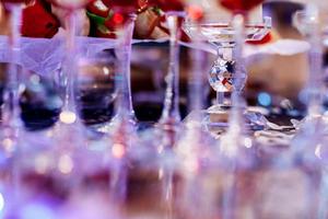 blurred focus legs of glasses on the table on luxury party. selective focus on crystal candlestick photo