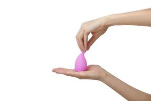 Pink menstrual cup. Close up of woman hand holding menstrual cup over white background. Women health concept, zero waste alternatives photo