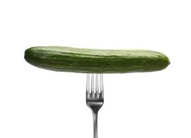 A fresh cucumber on a metal fork isolated on white background photo