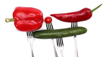 close up of fresh cherry tomato, red peppers and cucumber on forks on white background. Healthy eating and vegetarian food, cooking concept. photo