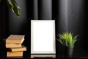 Stylish and modern workspace with white empty frame, books and houseplant on home or studio. High quality photo