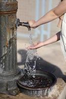 child hands under drinking fresh water tap on the beach on a bright Sunny day by the sea. High quality photo