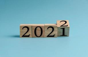 Wooden cube with word 2021 change to 2022. New Year concept on blue background. Closeup and copy space on top and under for design or text. photo