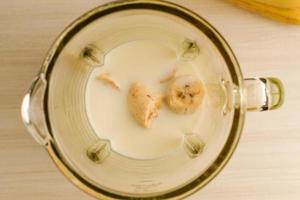 Banana blender mixed with fresh milk. Concept of making healthy drinks by yourself at home. Close-up shot with blurry wood background and nobody. photo