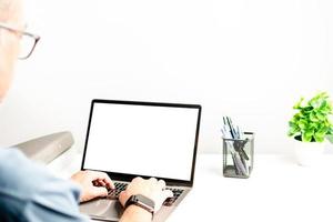 primer plano de manos masculinas, computadora portátil con una pantalla en blanco en una mesa en la oficina. concepto de trabajo usando un cuaderno, internet. copie el espacio a la izquierda para el diseño o el texto, el primer plano, el gris y el fondo borroso foto