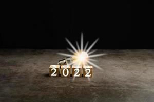 A bright light bulb on the work table. Concept of a startup that drives the economy, finance, banking, forward, future, glowing, startup, strategy, success, 2021 to 2022, Blurred, black background photo