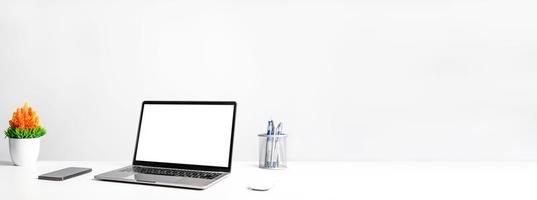 Working concept using technology, notebook, smartphones, devices. Blank white screen laptop on a white table in the office. Copy space on right for design or text, Closeup, Gray, and blur background photo