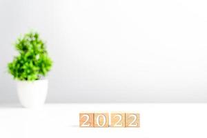 New year 2022 wood cube is on a work table. Concept of a startup that drives the economy, finance, banking, forward, future, glowing, startup, strategy, success. Copy space, Blurred, grey background photo