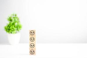 This smiley face wood cube happy smiley face icon gives satisfaction in service. rating very impressed. Customer service and Satisfaction concept. Copy space on right for design, text, Selective focus photo