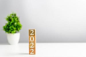 New year 2022 wood cube is on a work table. Concept of a startup that drives the economy, finance, banking, forward, future, glowing, startup, strategy, success. Copy space, Blurred, grey background photo