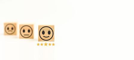 Customer service and Satisfaction concept. This Feedback with smile face wood cube happy smiley face icon to give satisfaction in service. rating very impressed. Black, Copy space, Selective focus. photo