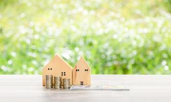 Simulated wooden house on the background grass blurred in the garden with a copy space upper side. The concept for real estate budget, Stack, money, coins, dollars, wooden, table. Selective focus. photo