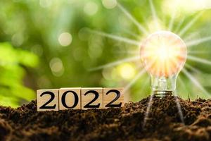 The new year 2022 and bright light bulb on the mound. Concept of a startup that drives the economy, finance, banking, forward, future, glowing, startup, strategy, success. Blurred, bokeh background photo