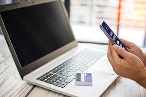 los hombres usan teléfonos inteligentes para comprar en línea. los empresarios transfieren dinero a través de Internet. la mano de un hombre sostiene un teléfono inteligente para el pago. foto