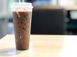 Close-up, iced coffee on a wooden table in the shop. Coffee cup with christmas icon. Copy space on right for design or text. Blurred background. photo