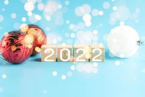 The wooden cube with the word 2021 changes to 2022. New Year Christmas Day. Concept on bokeh and blue background. Close up and copy space on top and under for design or text. photo