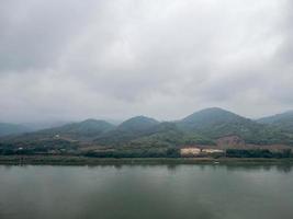 The mountain range is covered by clouds near the large river. photo