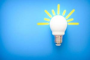 led light bulb with yellow rays on blue background photo