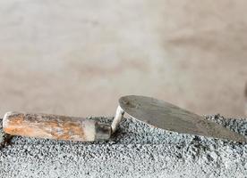 Dirty trowel on the incompleted brick wall. photo