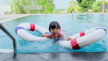 sorelline felici con anello di gomma in piscina. i bambini giocano nella piscina all'aperto del resort tropicale durante le vacanze estive in famiglia. bambini che imparano a nuotare. video