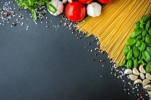 Pasta and ingredients for cooking on dark background, top view photo