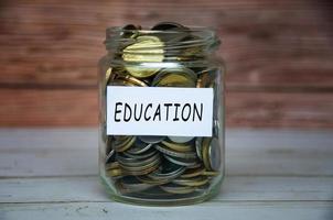Education label on coin jar on top of wooden desk with blurred background. Education concept photo