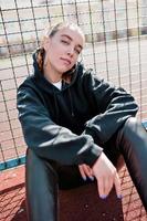 Independent pretty woman with collected hair wearing black outfit sitting outdoor in sunny day photo