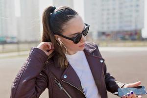 Attractive woman walking around in sunlight in sunglasses and leather jacket photo