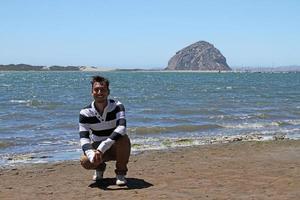 Young man kneeling near the sea in California photo