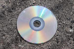 Old used compact disc on an asphalt road. Close up view. photo