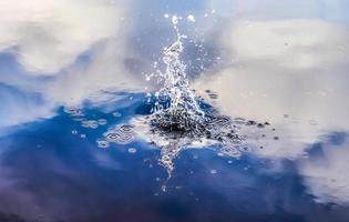 Beautiful water at a lake with splashing water and ripples on the surface with clouds and blue sky reflections photo