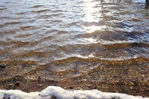 Detailed close up view on water surfaces with ripples and waves and the sunlight reflecting at the surface photo