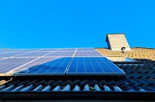 Solar panels producing clean energy on a roof of a residential house photo