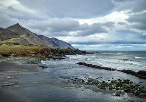 A rocky beach with bergs on Iceland in strong winds with powerful surf. photo