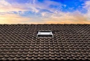 Roof window in velux style with dark roof tiles. photo