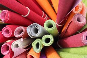 Close up view on rolled samples of cloth and fabrics in different colors found at a fabrics market.. photo