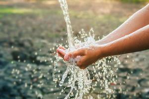 verter agua en la mano en el fondo de la luz de la mañana foto