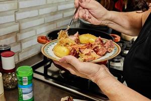 Chef puts the finished Alsatian sauerkraut on serving plate photo