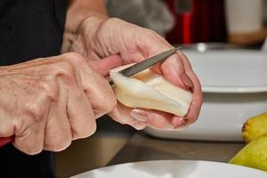 Chef cuts the pears into slices for chocolate cake with pear and nuts. Step by step recipe photo