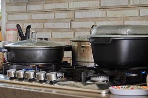 preparando comida en sartén y guisos en la estufa de gas en la cocina. concepto de cocina casera foto