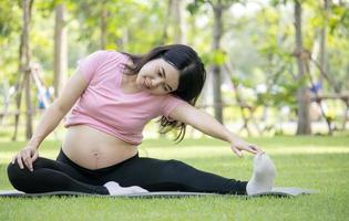 mujer embarazada asiática hace un entrenamiento matutino en el parque de vacaciones. concepto de ejercicio saludable foto