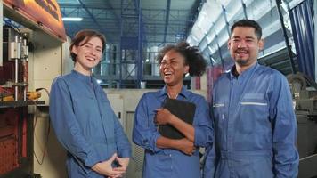 los trabajadores de la industria multirracial con uniformes de seguridad se relajan y se ríen juntos después del éxito en el trabajo, expresan felicidad con una sonrisa y son alegres en la fábrica mecánica. profesión de ingeniero profesional. video