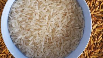 gros plan de riz blanc dans un bol et grains de paddy sur le fond. video